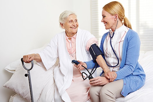Senior Woman With Nurse During Stroke Recovery Session.