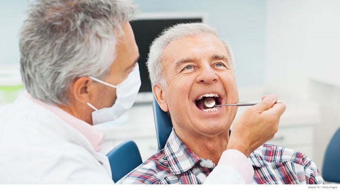 An image representing a dentist doing dental treatment of senior male patient.